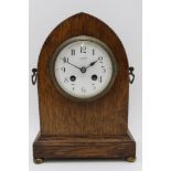 An oak lancet cased mantel clock, the white enamel dial with Arabic numerals, the dial inscribed '