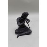 A cast metal model of an Eastern figure playing a one keyed flute, 23cm high