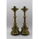 A pair of German Gothic design brass candlesticks, ring knop stems on weighted bases, each raised