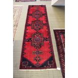 A woven woollen Sarab runner with triple geometric forms to plain pigeon red central field,