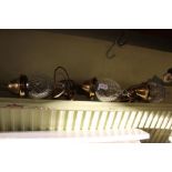 A trio of cut glass shaded hanging ceiling lights with brass fittings
