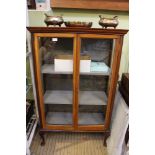 A 20th century glazed display case having two doors open to reveal upholstered shelved interior