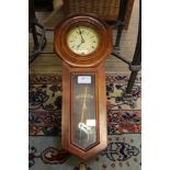 A small mahogany coloured framed hanging timepiece with display pendulum and key