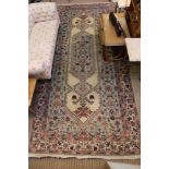 An elongated rectangular woven woollen floor carpet, geometric central motif stylised floral