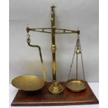 A late Victorian brass balance beam scale, raised on a polished mahogany base, by 'McClean & Co.,