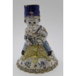A French faience hand bell, modelled in the form of a postman riding a tortoise, polychrome hand