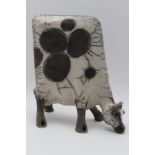 A Lawson E. Rudge, Raku pottery sculpture of a grazing cow, black & white, bearing No.25 on her