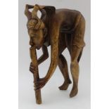 A 20th century carved wood indigenous female figure, blowing a musical instrument, 31cm high