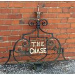 A 20th century wrought iron house sign, 'The Chase', black painted scroll work, with gilded flower