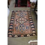 A woven woollen Heriz rug, having a trio of geometric lozenge to central field within a triple guard