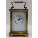 A late 19th century brass carriage clock, hinged bale handle, white enamel dial with Roman Numerals,