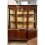 A first quarter 20th century mahogany finished display unit having chip carved frieze bowed glazed