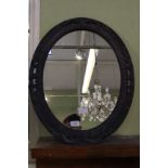 An oval plate wall mirror in dark grey felt effect pierced frame.