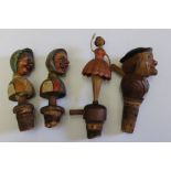 A collection of four mid 20th century carved wood Black Forest cork bottle stoppers