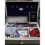 An ivory coloured jewellery box containing a varied selection of costume jewellery