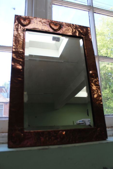 An Arts & Crafts copper framed rectangular bevel plate wall mirror, with a trio of heart motifs