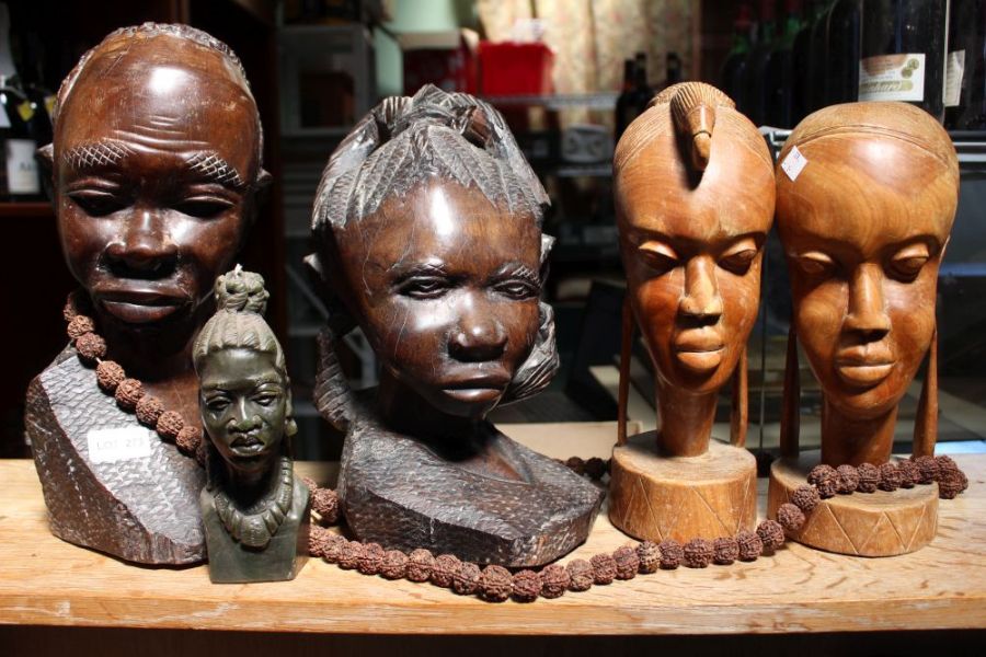 A selection of carved African Tribal heads, a good luck necklace and a candle