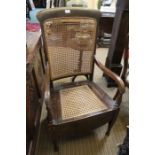 A late 19th century beechwood and cane work commode armchair