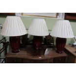 A trio of red porcelain, ribbed glazed table lamp