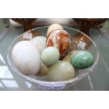 A glass bowl containing turned Onyx and mineral specimen eggs