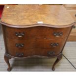 A reproduction serpentine fronted walnut finished three drawer chest