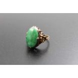 A 14k gold ring, decorative shoulders, inset an oval jade cabochon, gross weight; 4.5g