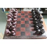 A carved wooden African figural chess set and board