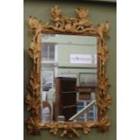A 20th century leaf carved and gilded frame housing a rectangular bevel plate wall mirror