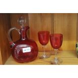 A 19th century red glass claret jug with stopper & two red plain stemmed glasses