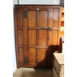 A Howard and Sons Ltd reproduction oak panelled cupboard the single door with mirror back opening to