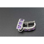 A pair of 18ct white gold earrings, each set three amethysts, surrounded by small diamonds