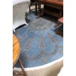 A large woven woollen oval floor rug, Wedgwood blue ground, with white stylised pattern