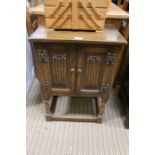 A reproduction oak finished small sized side cabinet, with twin linen fold cupboard doors