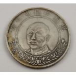 A Chinese silvered coin, a portrait to one side, and crossed flags to the other, 32mm in diameter