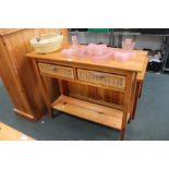 A modern pine side table with two wicker inline drawers, having solid undertier below