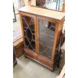 A small glazed bookcase with drawers to the base