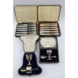 Two cased sets of egg cups with spoons, and two cased sets of silver handled knives
