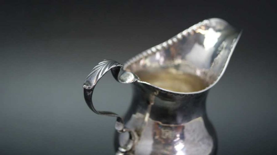 A George III silver cream jug of baluster form with punched rim, C scroll handle and raised circular - Image 5 of 5