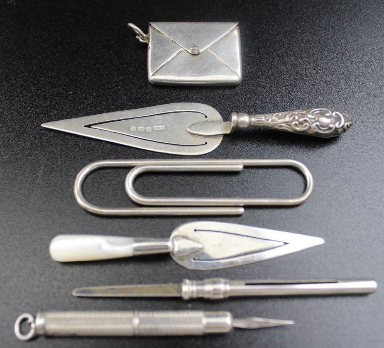 Two silver trowel bookmarks, silver stamp case, silver paper clip, and two silver toothpicks