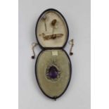 A 15ct gold brooch inset amethyst coloured stone, a pair of drop earrings, pendant withing a seed pe
