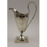 A George III silver helmet form cream jug, beaded rim and high hoop handle, on square platform base,