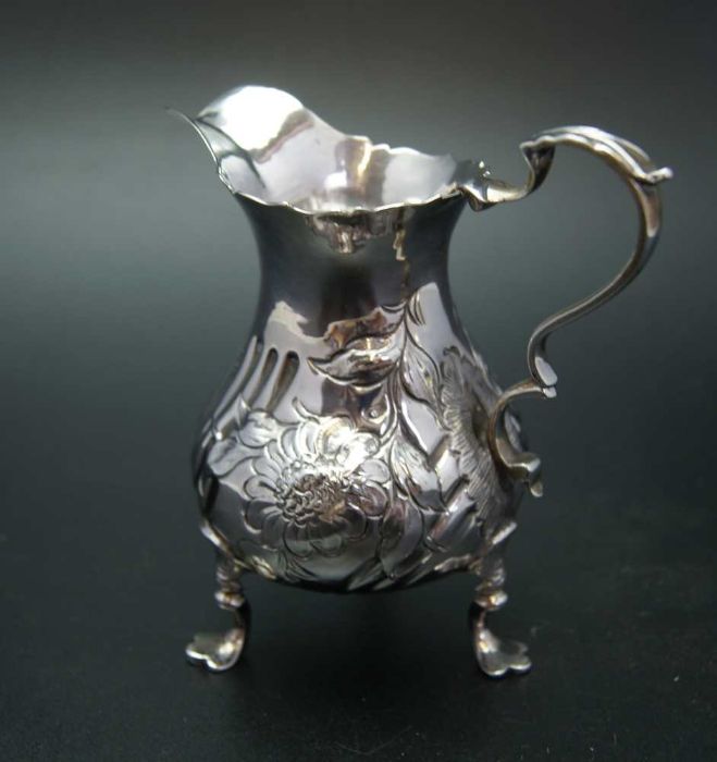 John Muns, a George III silver cream jug, embossed floral decoration, raised on three trefid support - Image 2 of 4