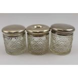 Three silver lidded cut glass dressing table jars, one being a hair tidy (two match Birmingham 1925)