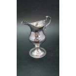 A George III silver cream jug of baluster form with punched rim, C scroll handle and raised circular