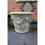 A large cast circular garden planter, decorated with figure heads and swags