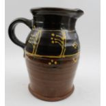A studio pottery glazed jug with step handle and slipware decoration 20cm tall