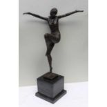 A reproduction bronze effect figure of a female dancer with arms outstretched, supported on a large