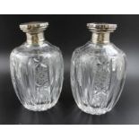 A pair of cut and faceted glass decanters, each with glass stopper beneath silver cover, stamped .95