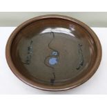 A Winchcombe pottery glazed bowl blue abstract design on a brown glaze 30cm diameter with empresses