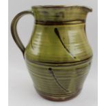 A studio pottery terracotta jug, with green glazed and strap work handle